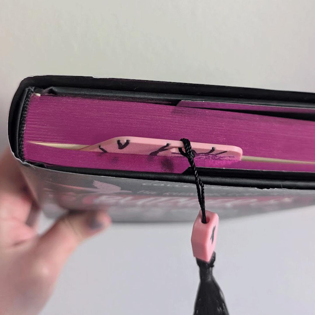 Bookmark in book being held by hand on a white background.