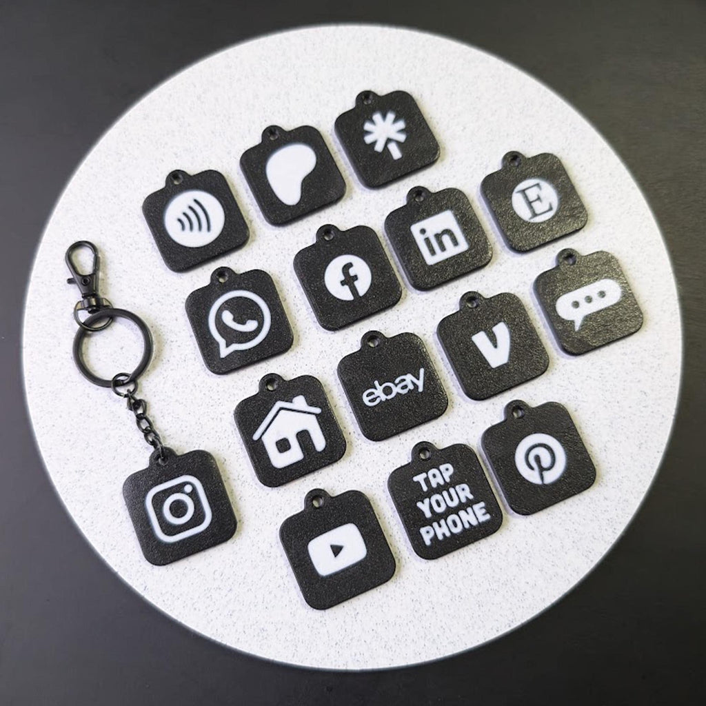 Set of black keychains with various app icons on a white circular mat