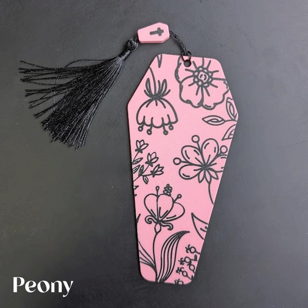 Pink coffin bookmark with floral patterns and a black tassel on a dark background