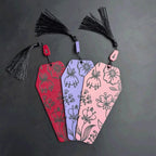 Three decorative coffin bookmarks with tassels on a dark background