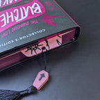 Pink coffin-shaped bookmark with tassel in a book.