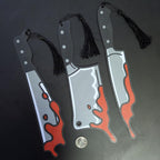 Bloody knife bookmarks with tassels on a dark background next to a quarter for size. 